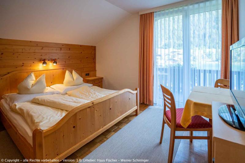 Eines unserer Zimmer mit Blick auf den Balkon, rechts der Fernseher, der Tisch mit den zwei Sesseln und links das Bett.