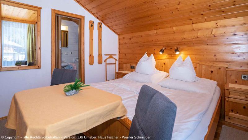 Eines unserer Zimmer mit Blick auf einen Tisch mit zwei Sesseln vor dem Bett. (aus einem anderen Winkel)