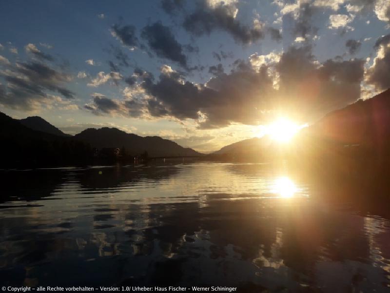 Blick auf den Weissensee mit den Bergen im Hintergrund während einem Sonnenuntergang.