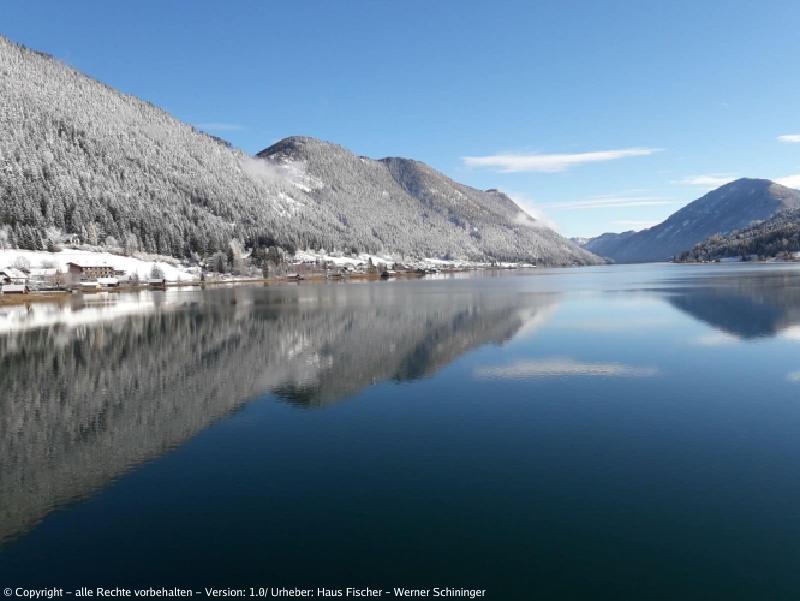 Blick auf den Weissensee mit den Bergen im Hintergrund, welche leicht mit Schnee bedeckt sind.